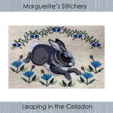 cross stitch design of a leaping gray rabbit with blue flowers below and above